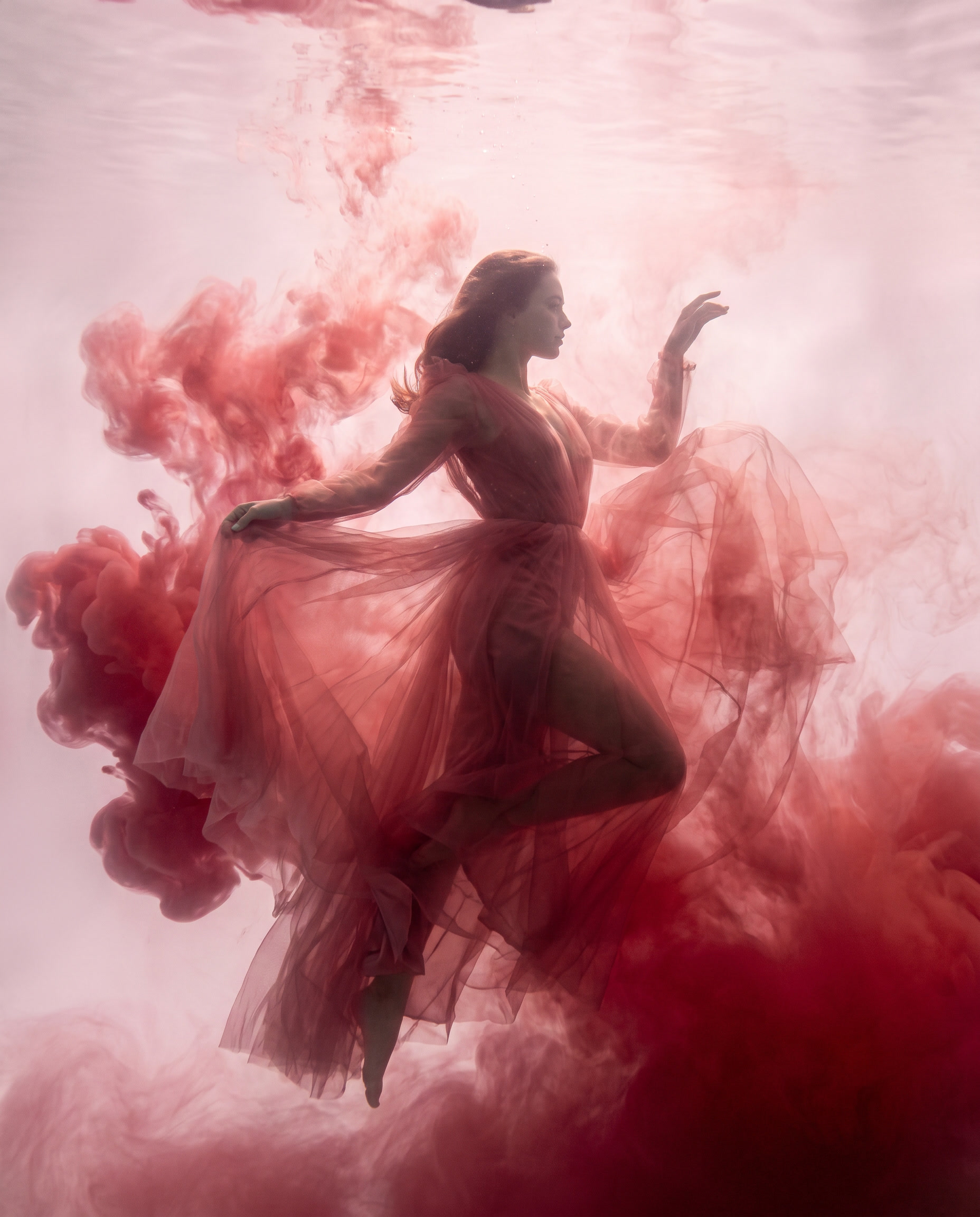 Fine art fashion photograph of an adult female dancer suspended underwater